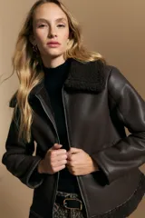 Campera tipo gamulán de cuero sintético en color marrón oscuro, con interior y cuello de corderito al tono. Presenta cierre frontal metálico y diseño de silueta relajada.