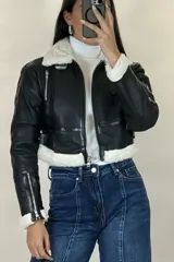 Campera tipo gamulán de cuero sintético negro, con interior y detalles de cuello y puños en corderito blanco. Presenta cierre frontal, cierres en los puños y correas ajustables en la cintura.