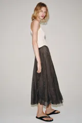 Falda midi de tiro medio de la colección ZARA Woman, confeccionada en mezcla de lyocell con acabado fluido y bajo en línea evasé. Cuenta con forro interior a tono y cierre lateral con cremallera oculta.