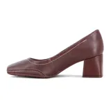 Zapato de taco cuadrado bajo, color marrón, con punta fina y costuras decorativas a la vista. Incluye un pequeño pin metálico dorado en el lateral.