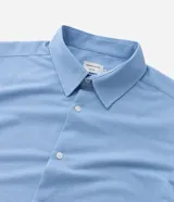 Camisa de manga larga color celeste, de corte slim, con cuello inglés y cierre frontal de botones.