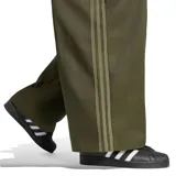 Pantalón Adidas Adicolor Sarga SST de corte holgado y pernera ancha, color verde militar. Presenta cintura elástica con cordón ajustable y las clásicas tres tiras de la marca a lo largo de los laterales. Incluye el logo del trifolio bordado en una pierna.