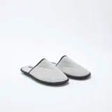 Pantuflas cerradas de tela gris con ribete negro.