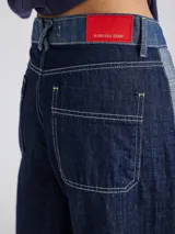 Pantalon ancho de denim en varios tonos de azul con diseño patchwork, de tiro medio y cierre frontal con botones.
