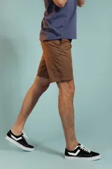 Bermuda de gabardina color tostado, de corte recto y largo por encima de la rodilla, con cierre y botón frontal.