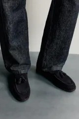 Mocasines de vestir para hombre confeccionados en piel con acabado en serraje de color azul marino, con detalle de borlas en el empeine y suela con ligero tacón.