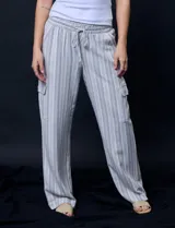 Pantalón cargo de lino a rayas verticales grises y blancas, marca Marissa Olivia. Pretina ancha elastizada con lazo de ajuste, bolsillos inclinados delanteros y bolsillos laterales con botón.