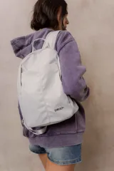 Mochila compacta de color beige, con compartimento principal con cierre, bolsillos laterales y bolsillo frontal con cierre oculto. Cuenta con correas regulables y acolchonadas y asa superior.