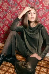 Remera de manga larga confeccionada en tejido de lurex negro con destellos dorados. Detalle de volados en el cuello tipo collar.