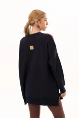 Buzo tejido de punto con silueta oversize y calce relajado. Presenta un diseño gráfico inspirado en una granada con bloques de color en azul marino, rojo y beige, cuello redondo y terminaciones en rib.