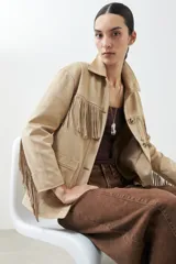 Chaqueta color beige de simil gamuza con flecos en el frente y en la espalda.