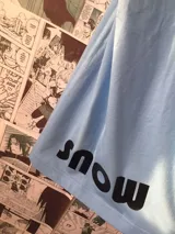 Remera celeste con estampado de un monstruo de nieve blanco y el logo de la serie Sk8: The Infinity.