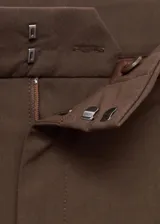 Pantalón de vestir marrón de tiro bajo y diseño wide leg, con pinzas frontales, trabillas para cinturón, bolsillos laterales y cierre oculto con botón, gancho y cremallera.
