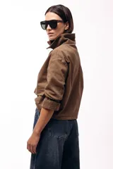 Campera corta color marrón, con cuello alto estructurado, cierre frontal y bolsillos delanteros con solapa. Presenta puños y cuello en tejido acanalado, con un diseño de corte recto y minimalista.