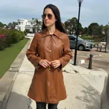 Chaqueta de cuero ovino color camel, con cuello clásico, corte recto y cierre frontal con botones a presión. Forrada en su interior.