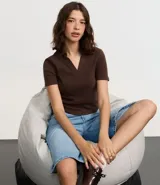 Blusa de cuello polo y manga corta, confeccionada en tejido rib de algodón con elastano. Presenta un diseño ajustado al cuerpo con escote en V y textura acanalada.