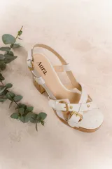 Sandalias de cuero color blanco con plataforma y taco de madera. Presentan tiras cruzadas con hebillas doradas y pulsera con hebilla al tobillo. Taco de 9.5 cm y plataforma de 3 cm.