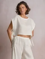 Blusa corta de lino marca Elan, de corte crop con silueta holgada, hombros caídos, escote amplio a la base y aberturas laterales ajustables con lazos para anudar.
