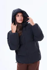 Campera puffer de corte holgado en color beige, con capucha integrada, cierre frontal completo y bolsillos laterales. Presenta un diseño acolchado con acabado mate y puños elásticos.