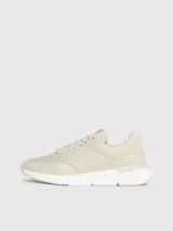 Zapatillas deportivas de mujer Calvin Klein, color beige claro, con cordones y suela gruesa blanca. Presentan una combinación de materiales que incluye piel natural y ecológica, con paneles de malla y detalles de monograma sutil en el lateral.