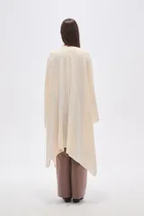Poncho abierto color crudo, de diseño holgado y caída fluida.