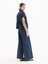 Pantalón wide leg de tiro medio-alto, confeccionado en denim de algodón azul con patrón de cuadros. Cuenta con recortes laterales que aportan volumen y caída fluida, además de bolsillos delanteros y traseros.