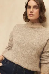 Polera beige de tejido de punto con cuello alto y mangas largas.