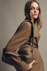 Bolso alargado tipo bowling color verde oliva, confeccionado en cuero con doble asa de mano y asa bandolera extraíble. Incluye bolsillo interior con cremallera y cierre principal con cremallera.