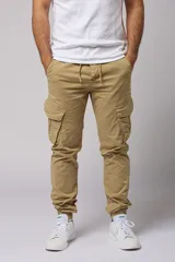 Pantalón cargo color beige de gabardina, con corte ajustado, bolsillos laterales con fuelle y puños elásticos en los tobillos.
