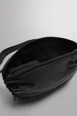 Riñonera deportiva plegable de tejido técnico, color negro. Cuenta con compartimento principal con cierre, bolsillo frontal con cierre, bolsillo plano posterior, asa ajustable con hebilla de liberación rápida y detalle de logo estampado.