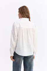 Blusa de algodón en color celeste, con textura sutil, cuello con volados y mangas largas con puños también decorados con volados. Presenta cierre frontal con botones.
