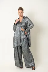 Camisa plateada de poliéster con textura metalizada, corte amplio, cuello clásico, cierre frontal con botones y mangas largas con puños abotonados.