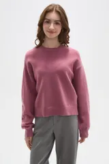 Sweater de tejido de punto color rosado, con cuello redondo, mangas largas y diseño holgado.