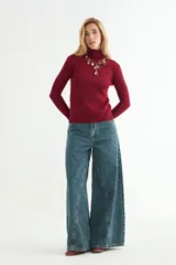 Jean de corte wide leg con diseño de costuras verticales decorativas en el frente, tiro medio y cierre frontal con botón y cremallera.