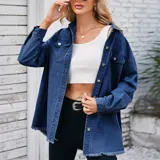 Campera tipo sobrecamisa de denim en tono azul claro, con corte oversize, cuello italiano, cierre frontal con botones metálicos, bolsillos frontales con solapa y ruedo con detalle desflecado.