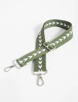 Correa de poliéster color verde militar con bordado de flechas blancas y herrajes metálicos plateados. Incluye mosquetones y hebilla regulable.