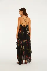 Vestido largo negro con tirantes finos, escote recto y diseño escalonado con capas superpuestas de volados con estampado floral.