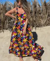 Vestido largo con estampado de hojas de colores sobre fondo negro, con breteles finos y falda con volados.