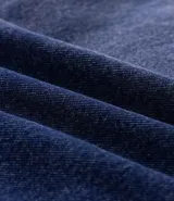 Campera de jean de corte oversized, con cuello de terciopelo, cierre frontal por botones y bolsillos grandes aplicados en el frente.