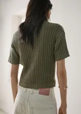 Chaleco de punto verde militar con diseño texturizado, cuello camisero, manga corta y cierre parcial de botones en la parte delantera.