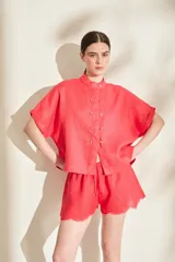 Blusa negra de lino de silueta amplia, con cuello mao y doble hilera de botones dorados en el frente. Cuenta con mangas cortas con vuelta.