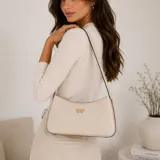 Cartera tipo bandolera Guess modelo Cerelia, color blanco hueso, fabricada en símil cuero con herrajes dorados y logo frontal de la marca. Cuenta con correa fina para el hombro y cierre superior.