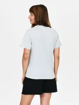 Remera de algodón color celeste con estampa frontal circular que incluye texto y diseño floral.