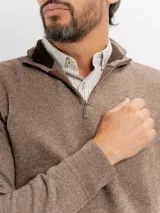 Buzo de tejido de punto color azul con textura jaspeada, cuello alto con cierre frontal parcial y puños acanalados.