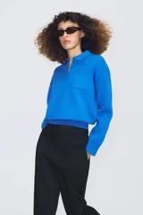 Jersey de punto con cuello tipo polo, manga larga con puños y cierre frontal con botones. Presenta un bolsillo de plastrón en el pecho y diseño de corte holgado.