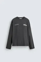 Camiseta de manga larga y cuello redondo con corte relajado, color gris oscuro, con estampado de texto en contraste en el pecho.