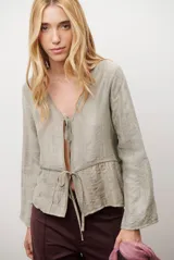 Chaqueta ligera de manga larga en color azul, con escote en V y cierre frontal mediante dos lazos ajustables. Presenta un diseño fluido con textura sutil y corte recto.