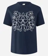 Remera de algodón color azul marino, con cuello redondo, mangas cortas y un bordado frontal en color blanco con diseño simétrico de motivos florales.