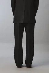 Pantalón de vestir regular fit confeccionado en lino, con pliegues frontales, bolsillos laterales y bolsillos traseros de doble vivo con botón. Presenta cierre frontal con cremallera y gancho metálico oculto.