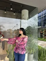 Blusa con hombros descubiertos, estampado floral en tonos rosados y mangas largas abullonadas.